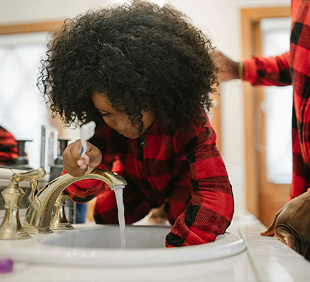 A girl brushes her teeth at a bathroom sink