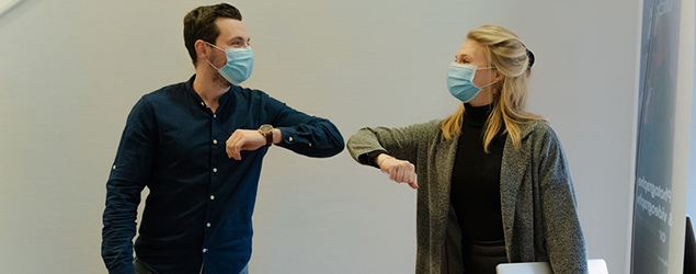 Two people greeting each other by bumping elbows