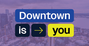 Downtown is you logo overlayed on a purple background with an aerial view of the Seattle skyline.