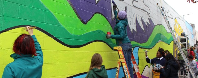 People painting mural on building