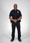 This photo shows a Seattle Police Department Officer standing head-on, wearing his police uniform.