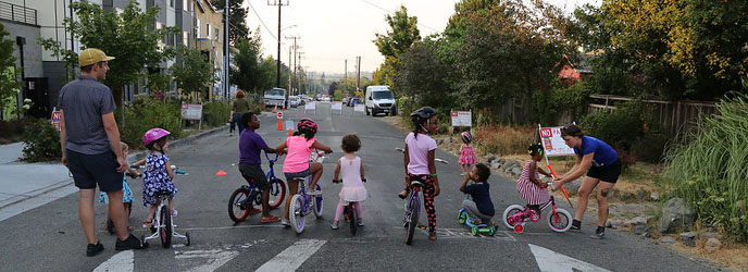 Children on bicycles along with adults assisting