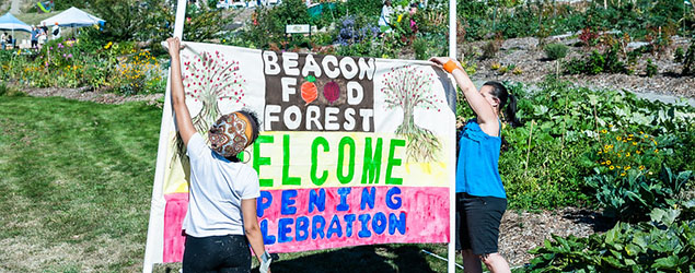 2 people holding up Beacon Food Forest welcome banner