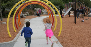 Two children running down a path through colorful arches