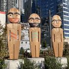 Three wooden figures facing the water next to Pier 58